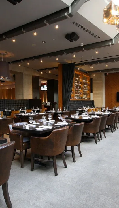 A modern dining room with dark wood furniture and warm lighting.