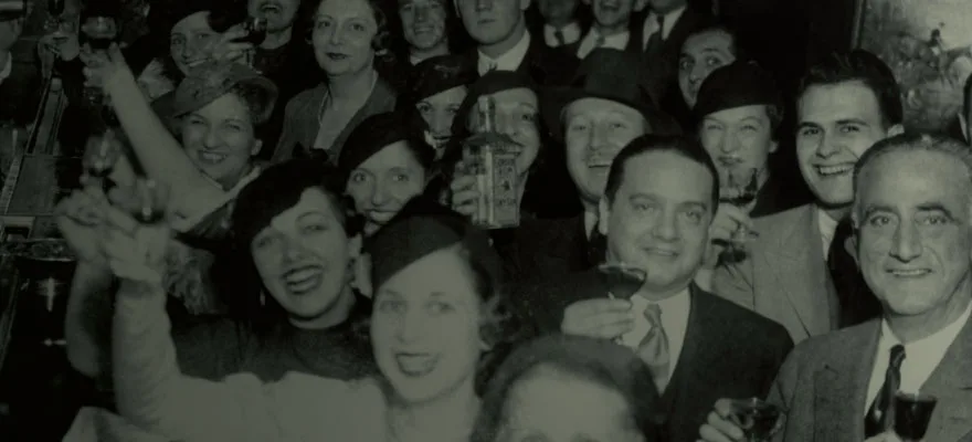 A crowd of people celebrating with drinks at a vintage event.