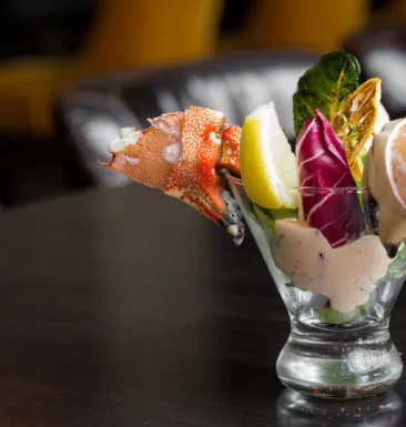 Seafood cocktail with lobster and garnishes in a glass.