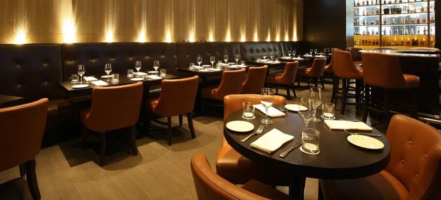 A sleek restaurant interior with leather seating and tables.