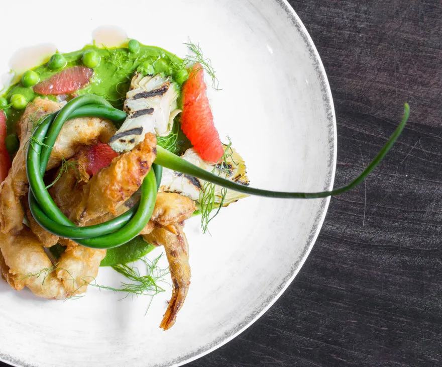 Battered soft shell crab with green pea puree and garnishes.