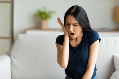 A woman in pain sitting on a couch.