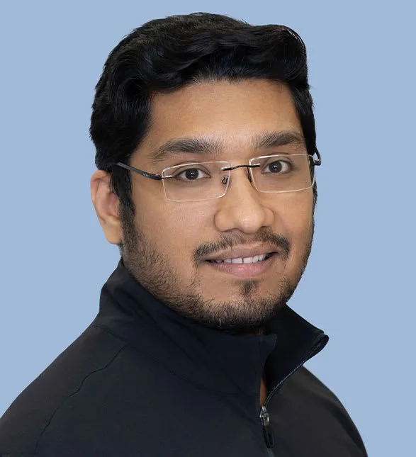 A friendly dentist smiling against a light blue background.