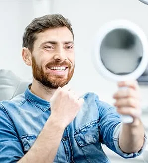 A man smiling while looking in a mirror in a dental clinic.