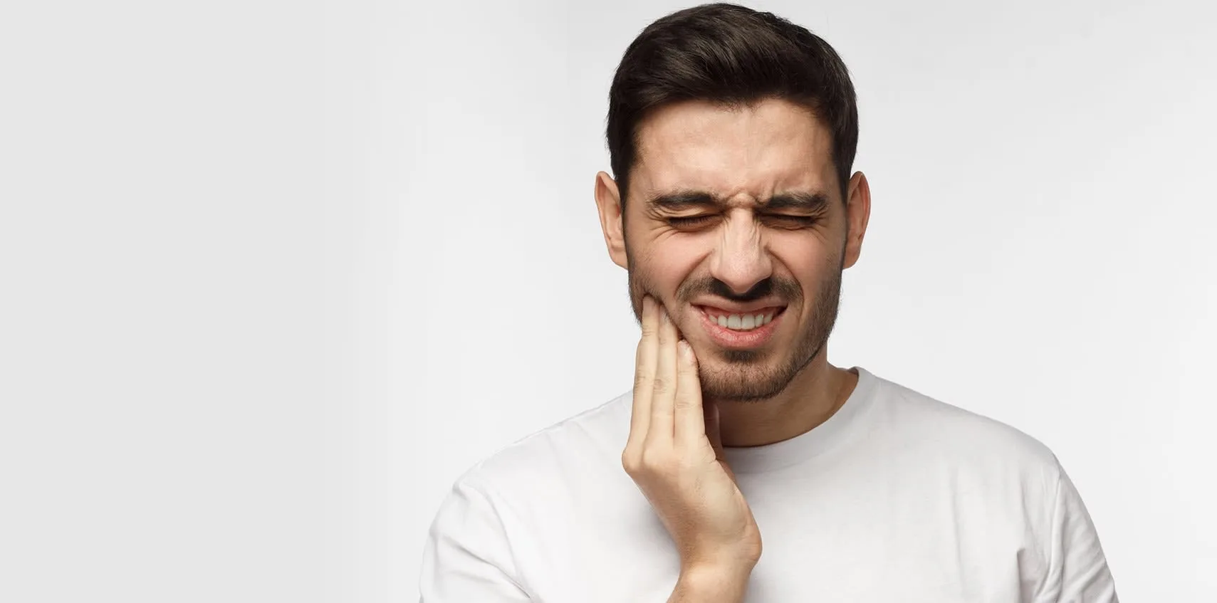 A young man in pain holding his jaw.