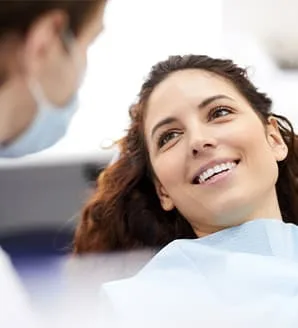 A smiling woman in a dental chair at a clinic.