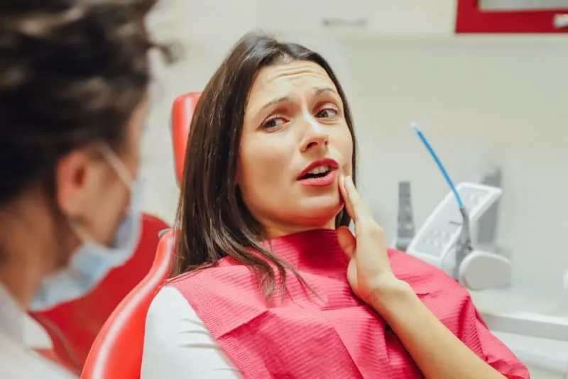 A woman in pain during a dental consultation.
