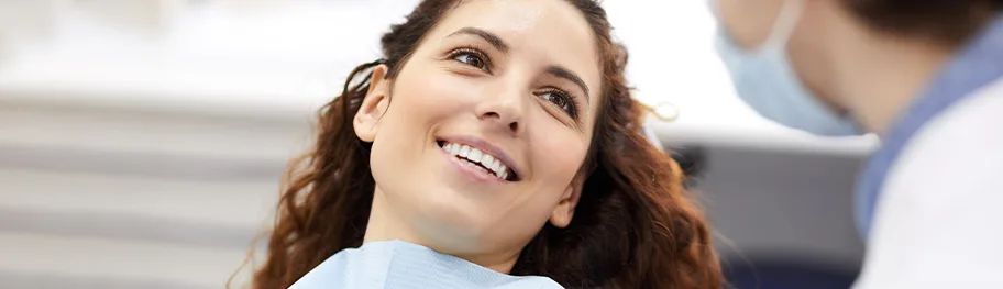 A woman smiling in a dental chair during a consultation.