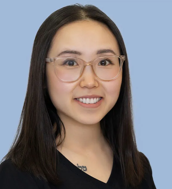 Smiling woman with glasses on a blue background.