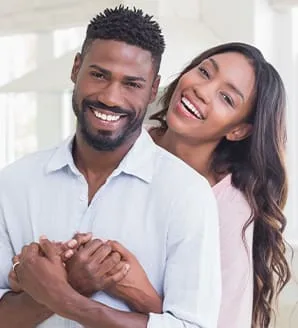 A smiling couple embracing in a bright interior space.