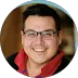 A smiling man with glasses in a red shirt.