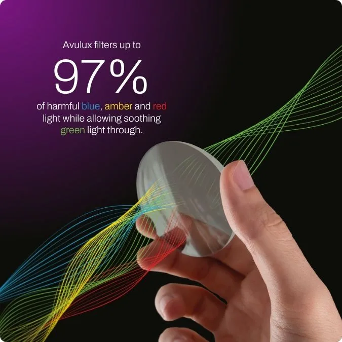 A hand holding an Avulux lens with colorful light waves.