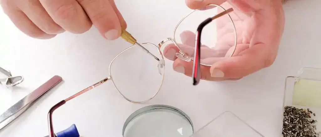 Hands adjusting eyeglasses at a repair station.