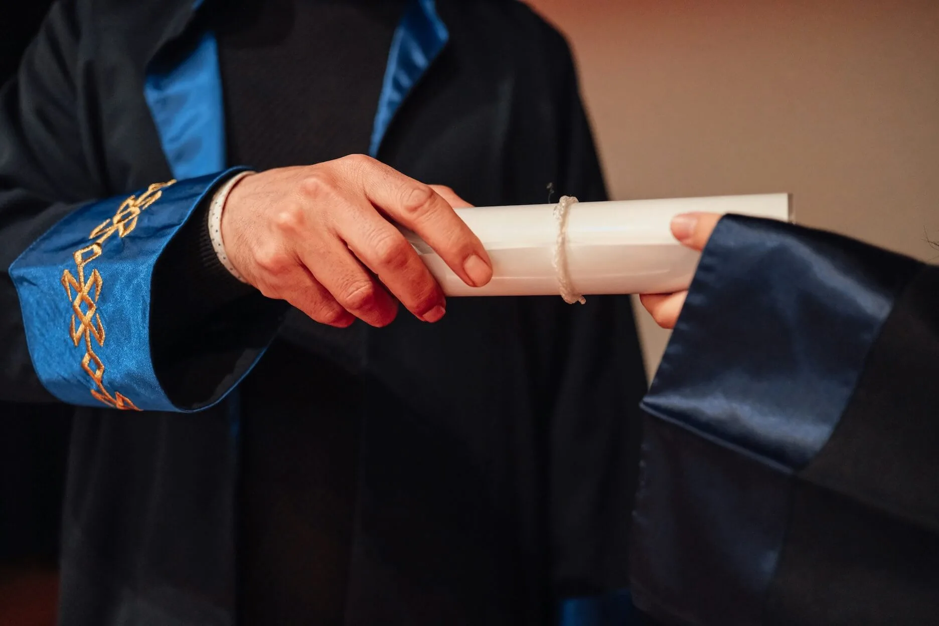 Graduates exchanging a diploma during a ceremony.
