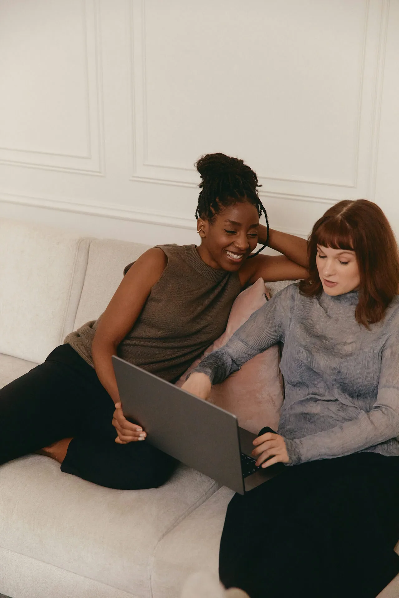 Two women collaborating on a laptop in a cozy setting.