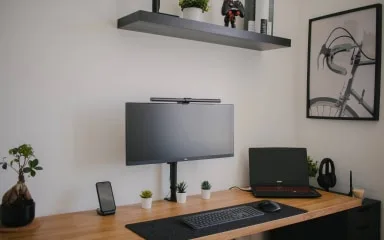 A modern workspace with a monitor and laptop on a wooden desk.