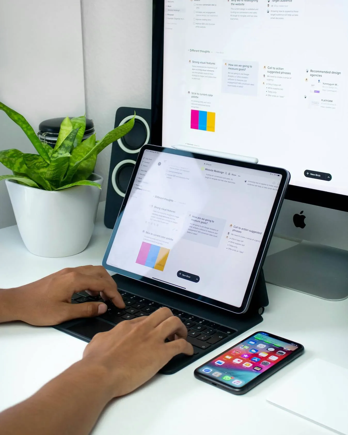 A person typing on an iPad in a clean workspace.