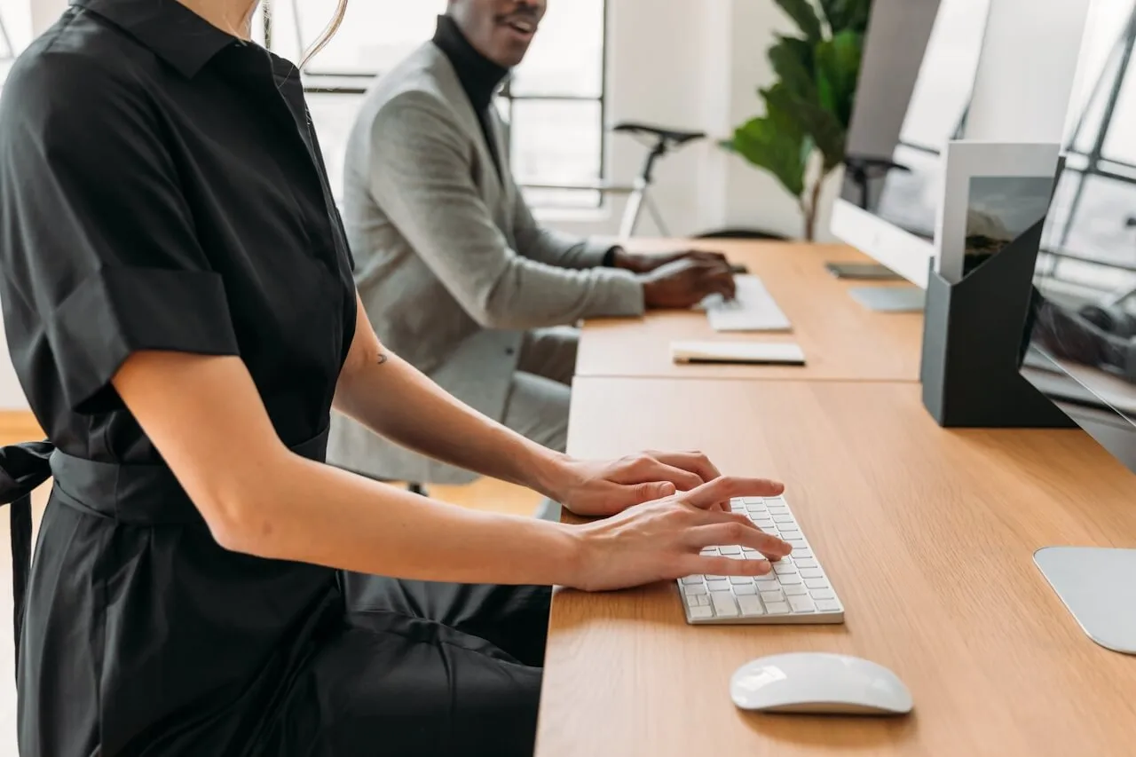 Two professionals working at a modern desk with computers.