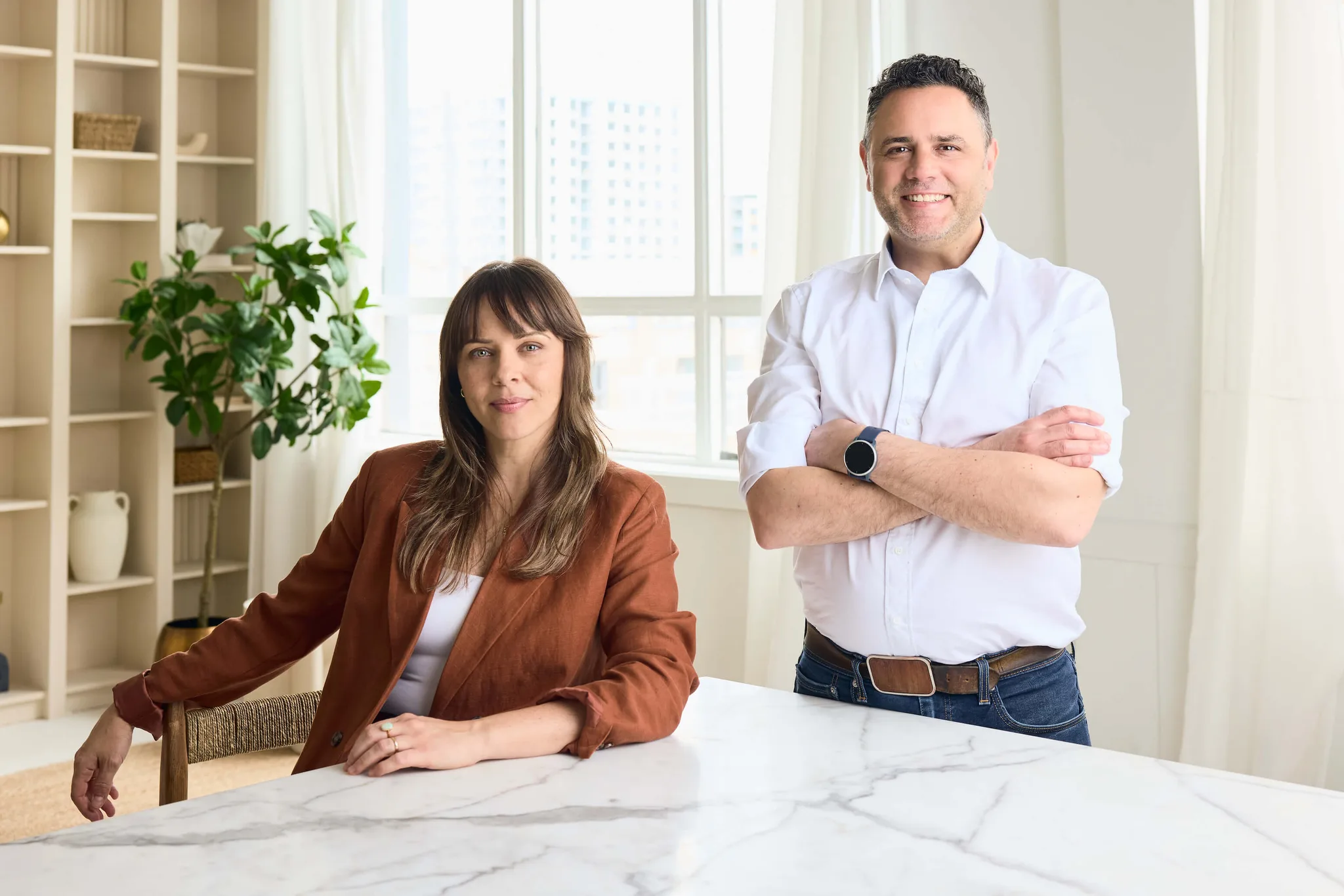 Two professionals posing in a bright office setting.