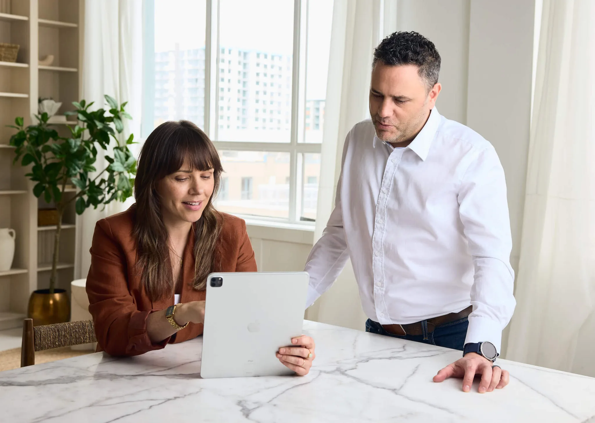 Two people collaborating over an iPad at a table.
