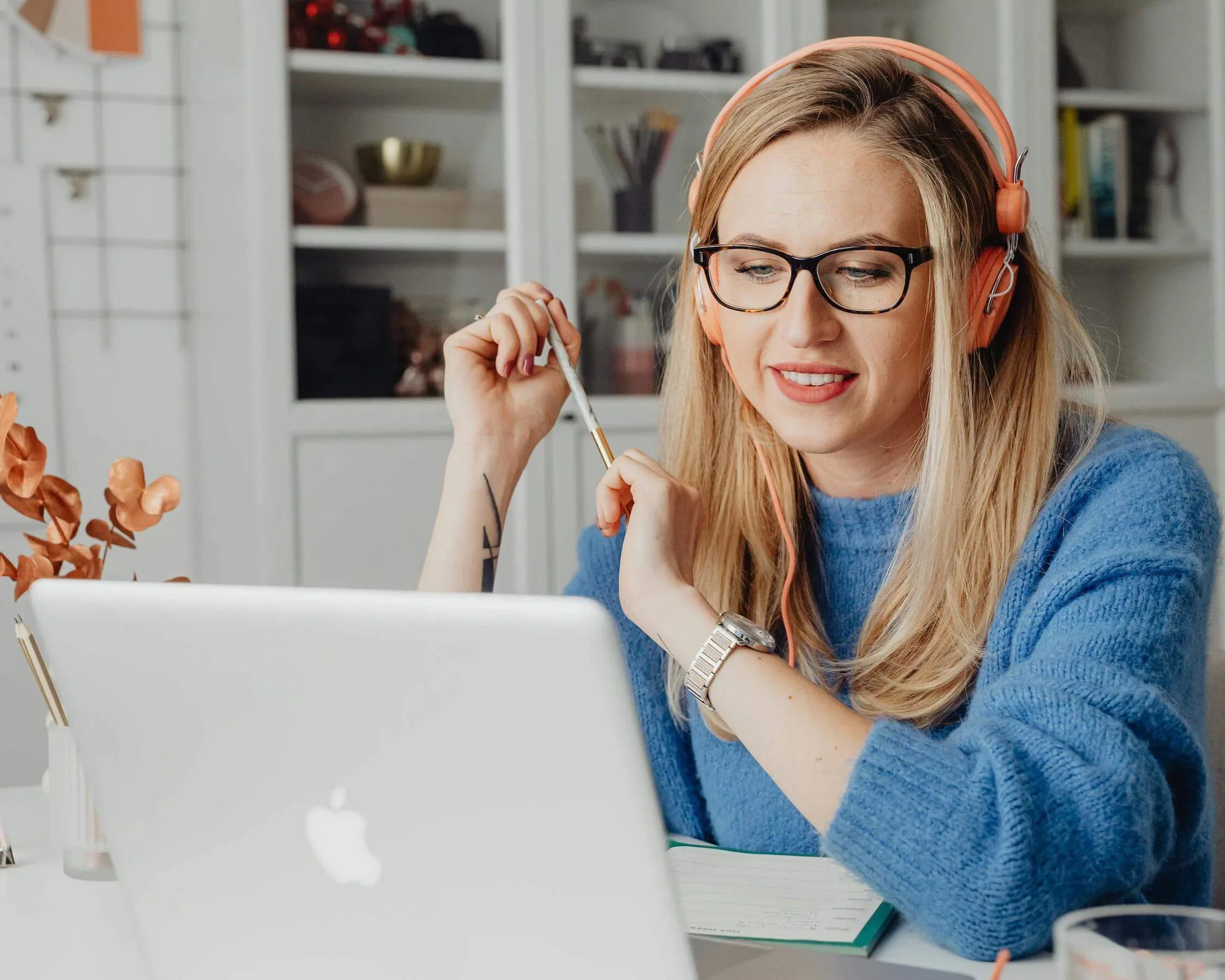 A woman in headphones engaging with a laptop at her desk.
