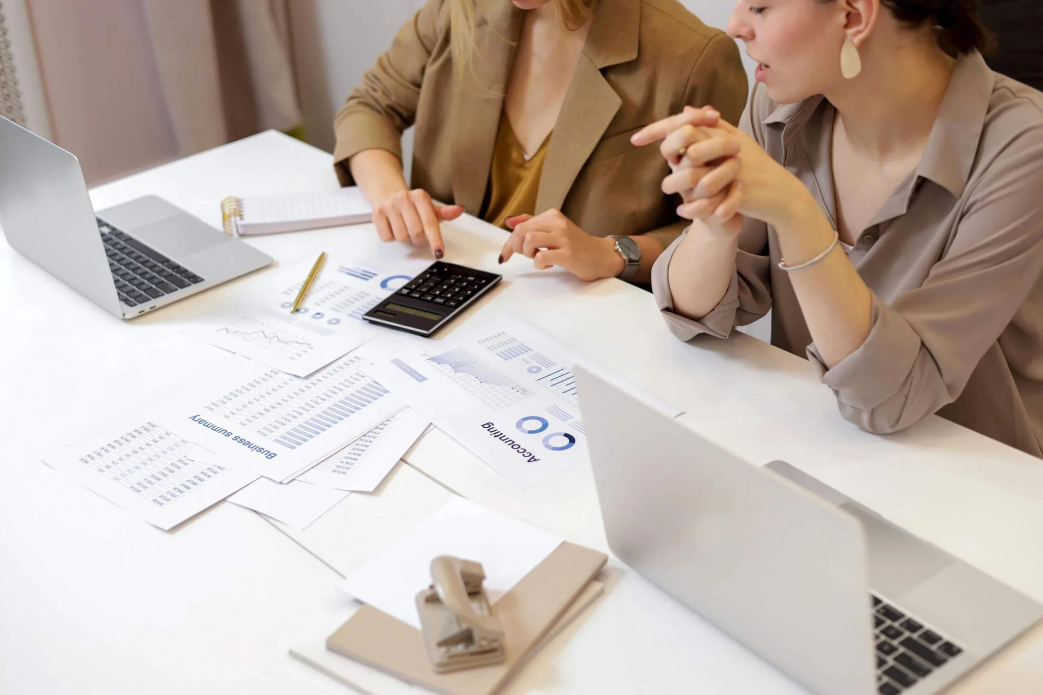 Two women discussing financial documents on a table.