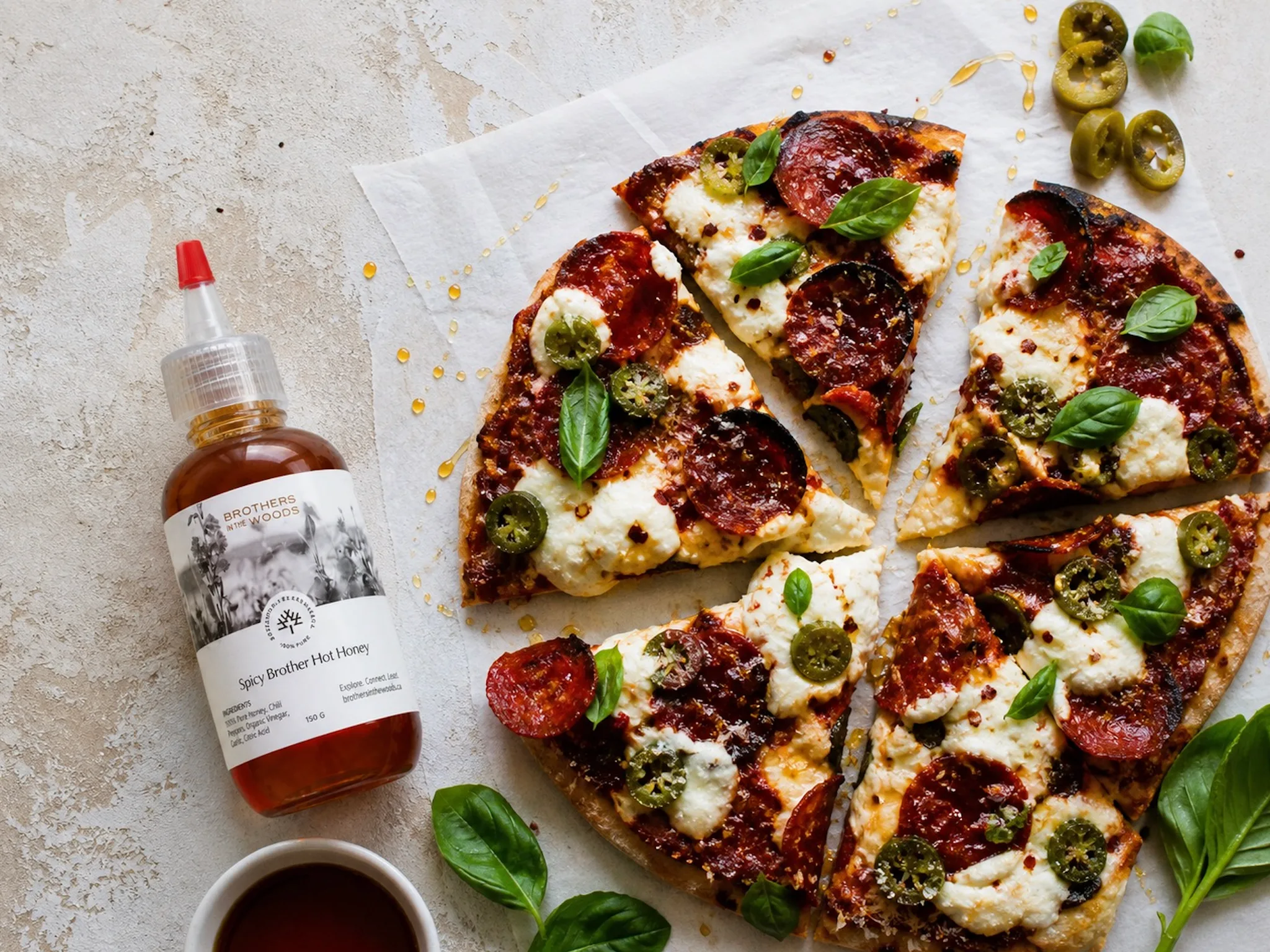 A pizza with pepperoni and a bottle of hot honey.