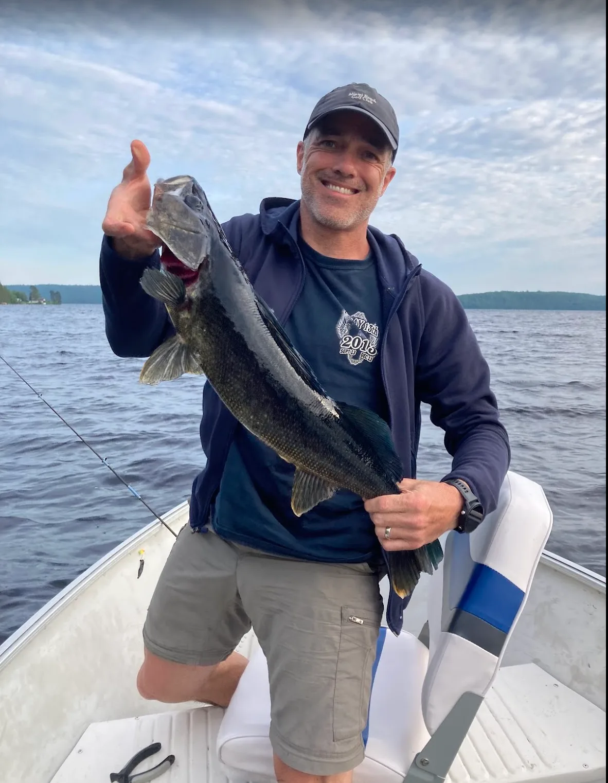 A man holding a large walleye fish on a boat.