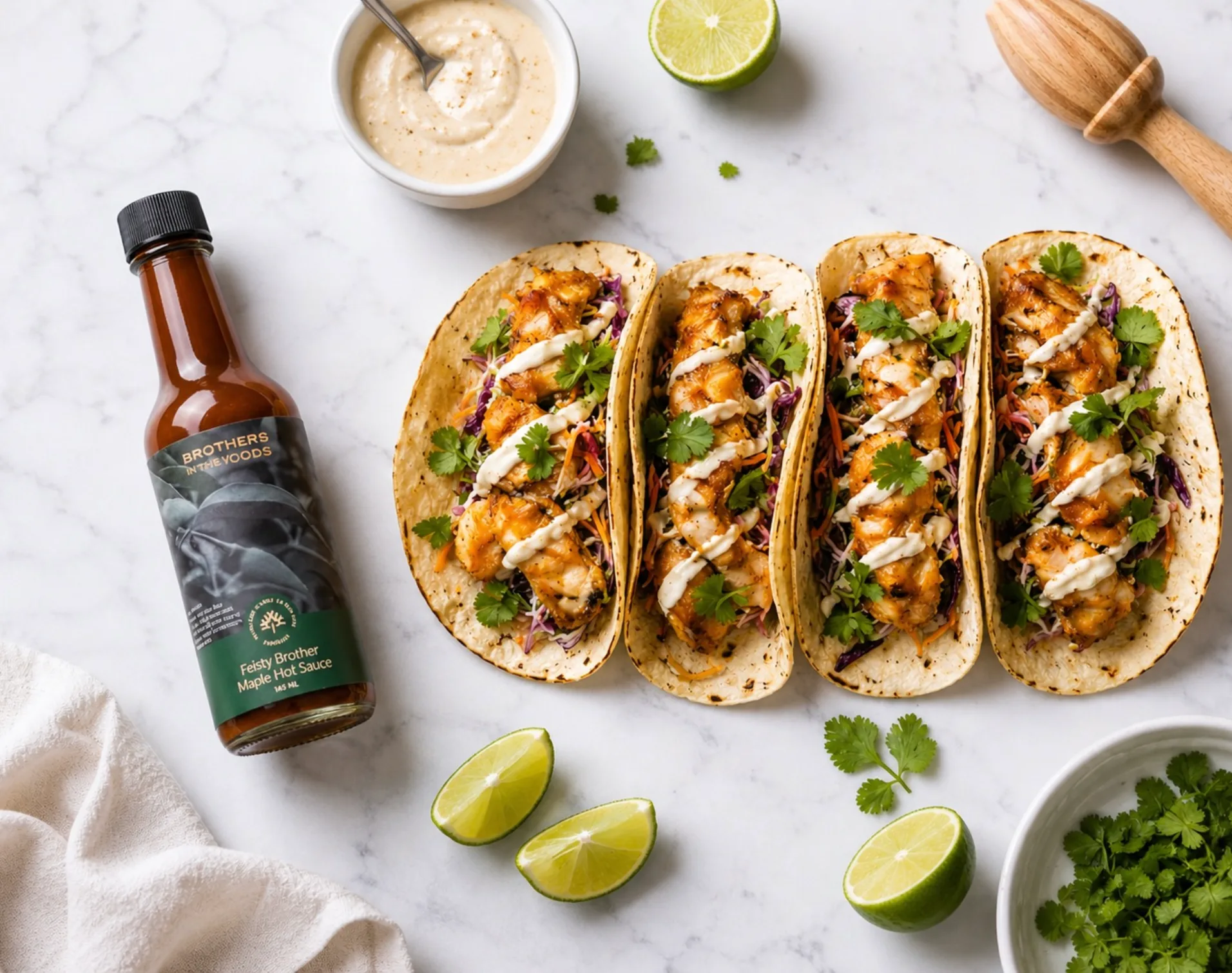 A plate of fish tacos with sauce and lime wedges.