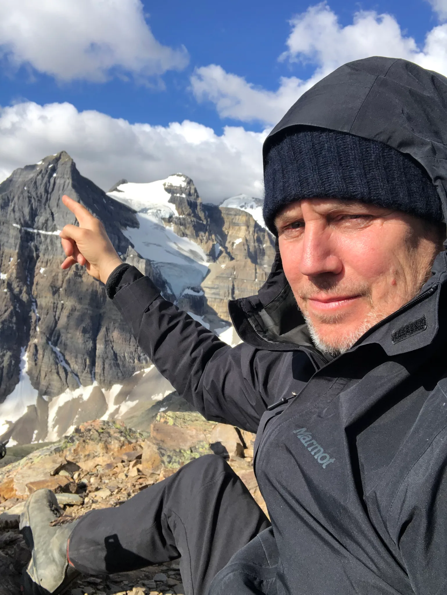 A man pointing at a mountain peak in a rugged landscape.