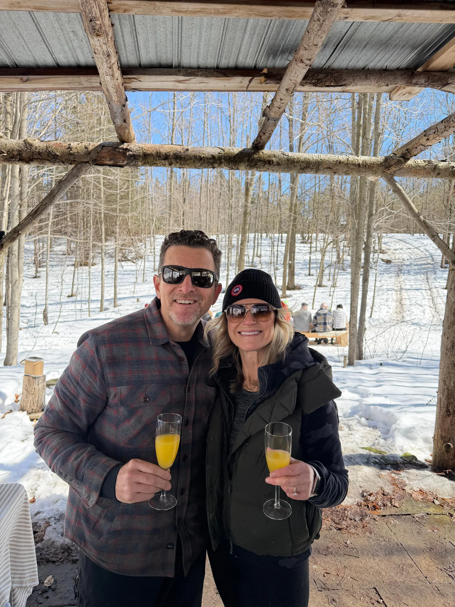 A man and woman holding drinks in a snowy outdoor setting.