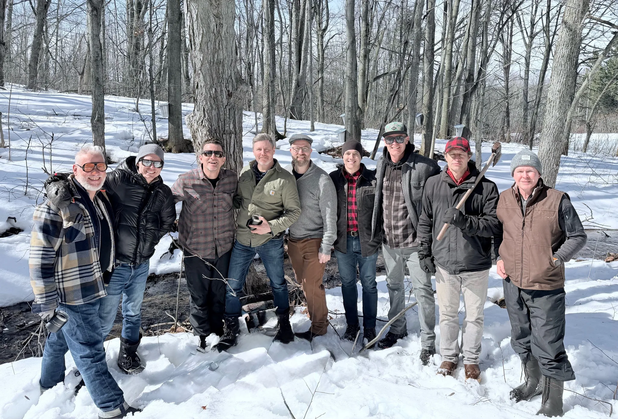 A group of men in winter attire in a snowy forest.