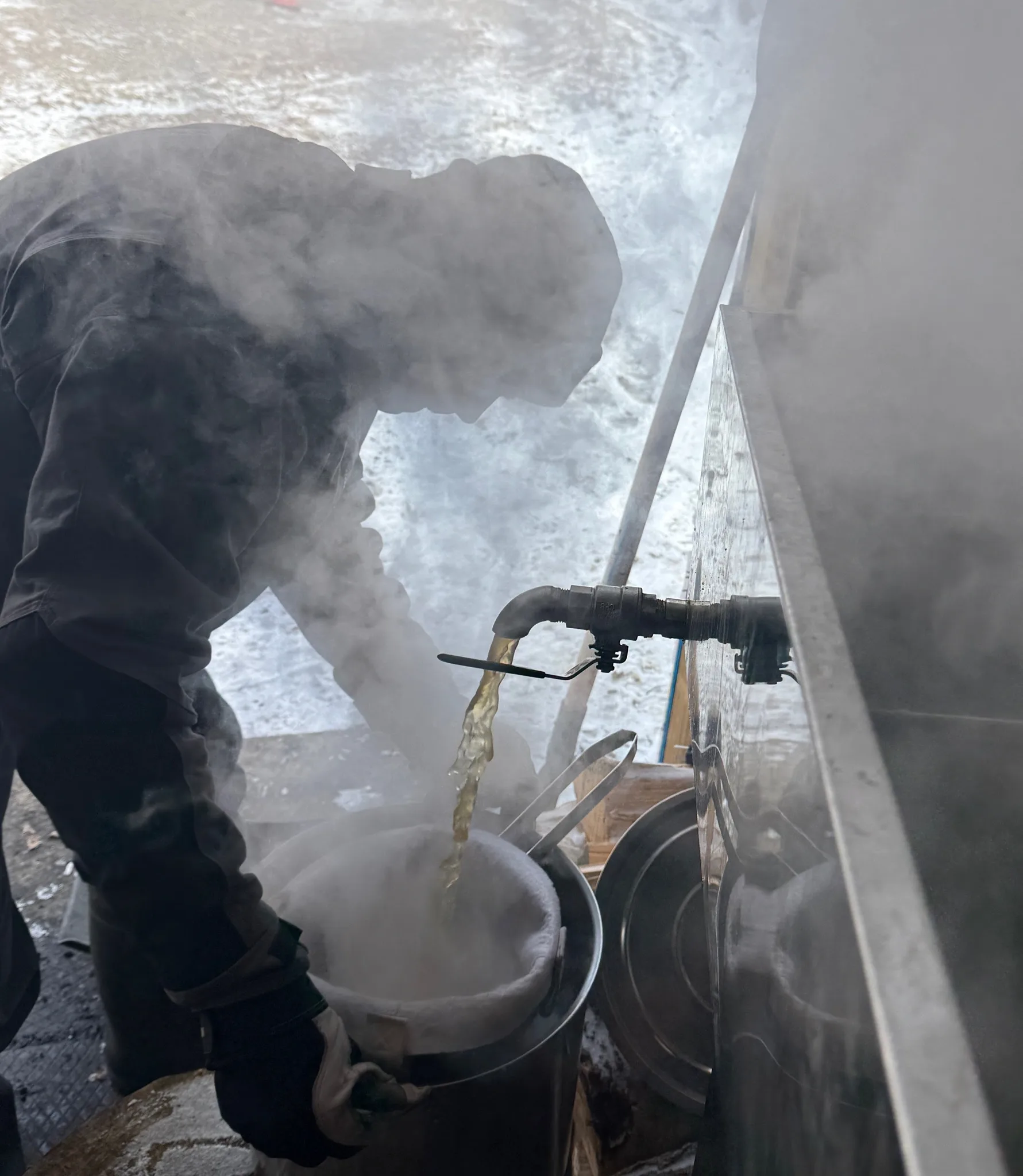 A person pouring warm maple syrup outdoors in winter.