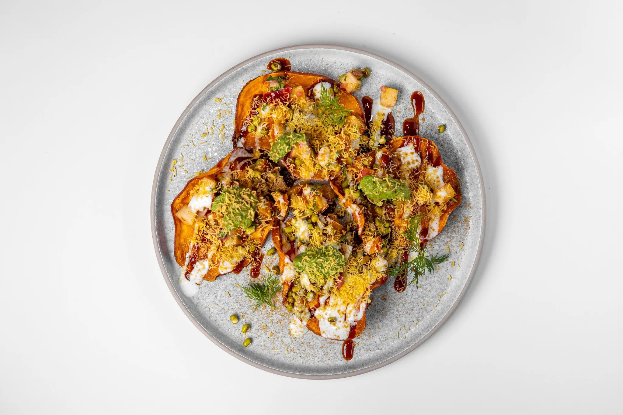 A plate of Indian-style nachos with diverse toppings.