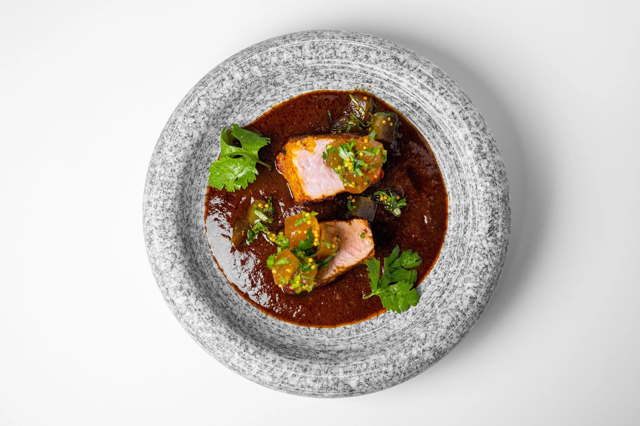 Salmon fillet served in a dark sauce with garnishes.