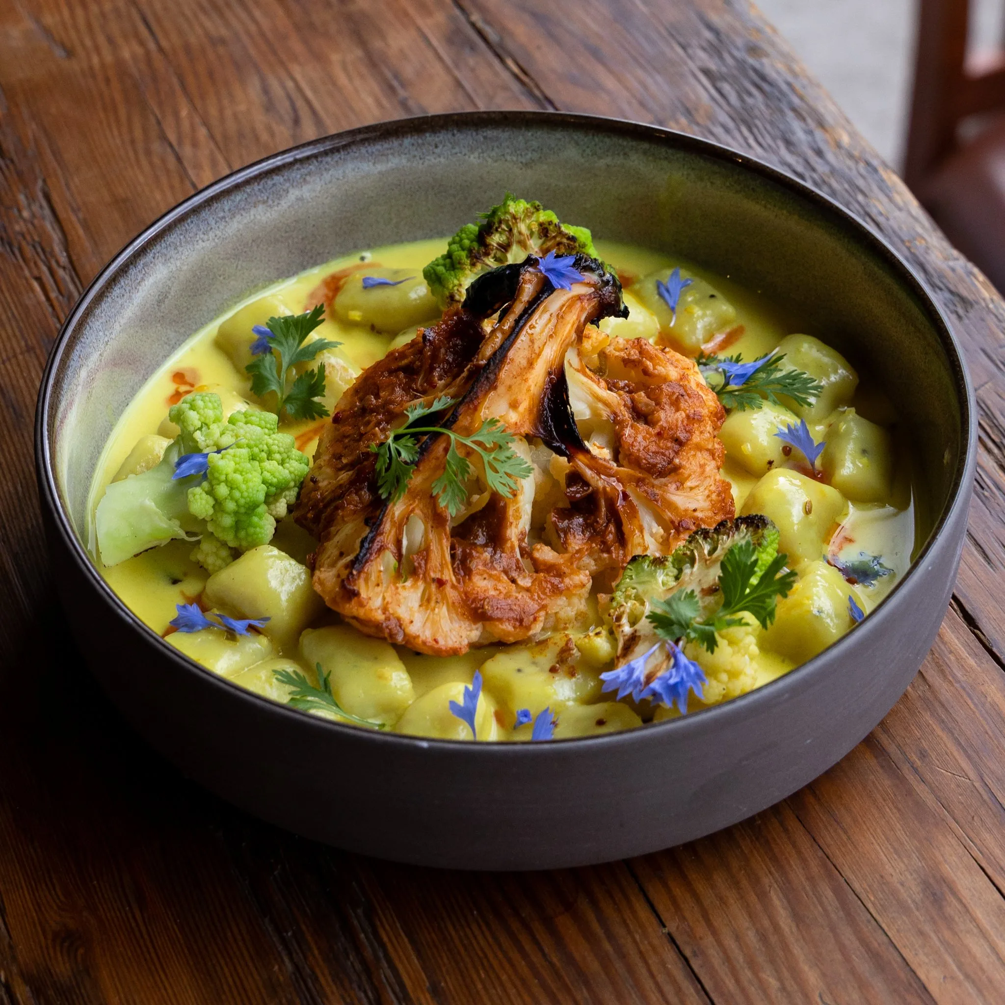 A bowl of curry with roasted cauliflower and vegetables.