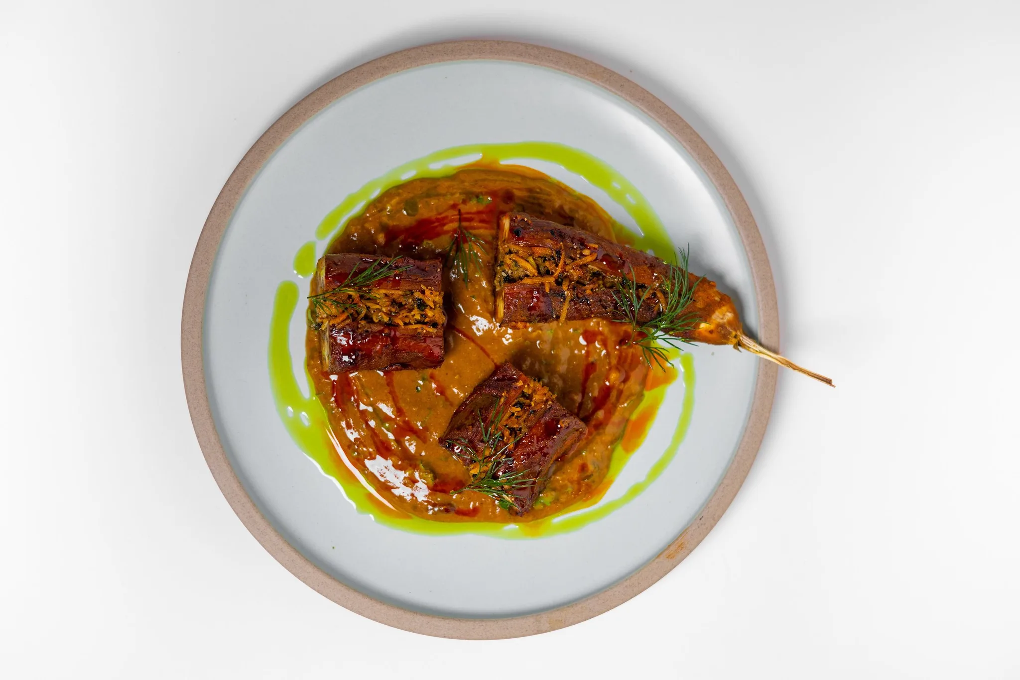 Grilled meat skewers served with sauce and herbs.
