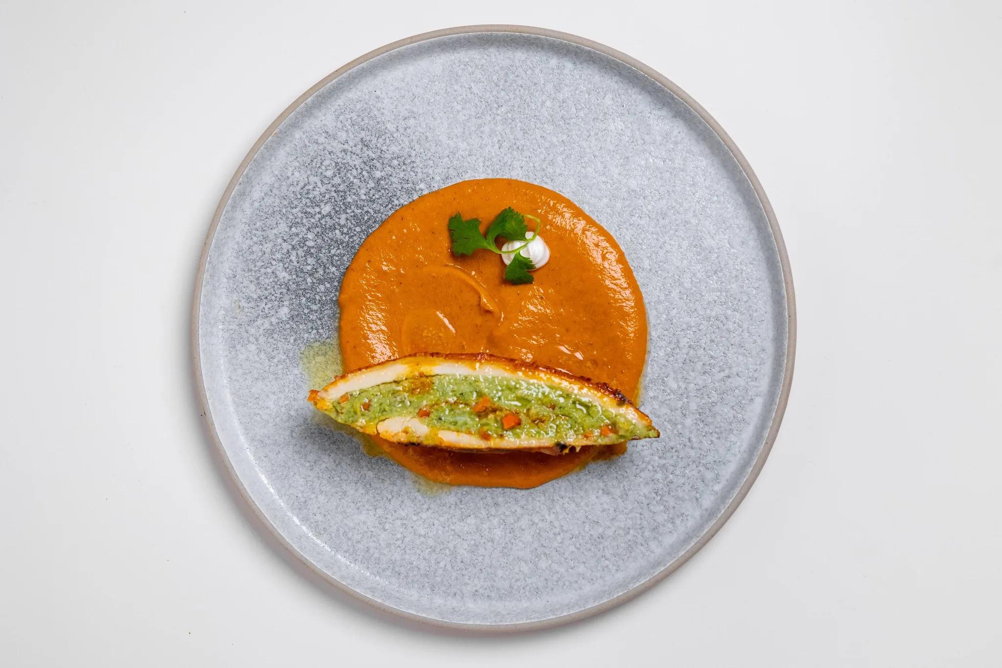 Grilled chicken served on orange sauce with cilantro garnish.