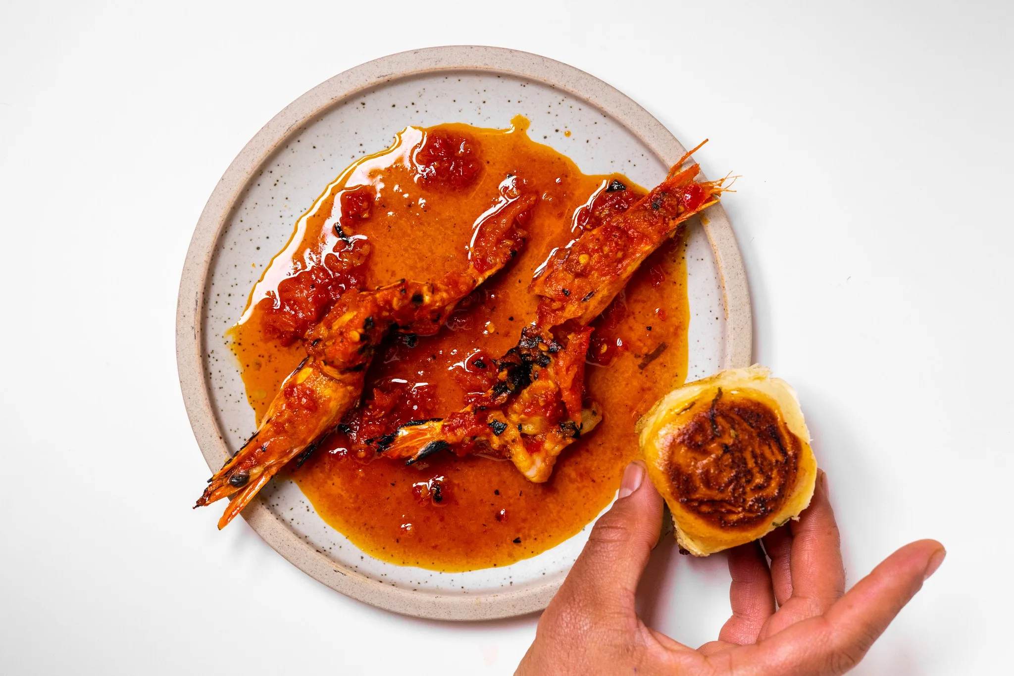 Grilled prawns with sauce and a buttered bun.