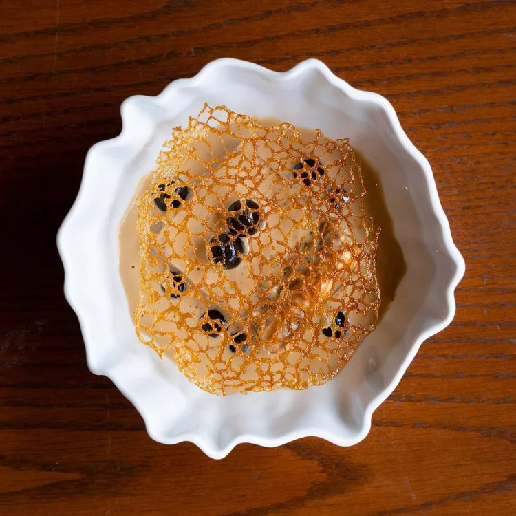 A dessert with a caramelized sugar garnish in a white bowl.