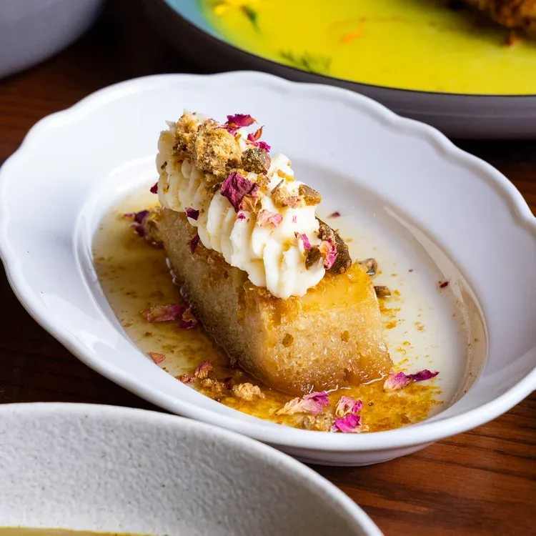 A slice of Indian dessert with cream and rose petals.