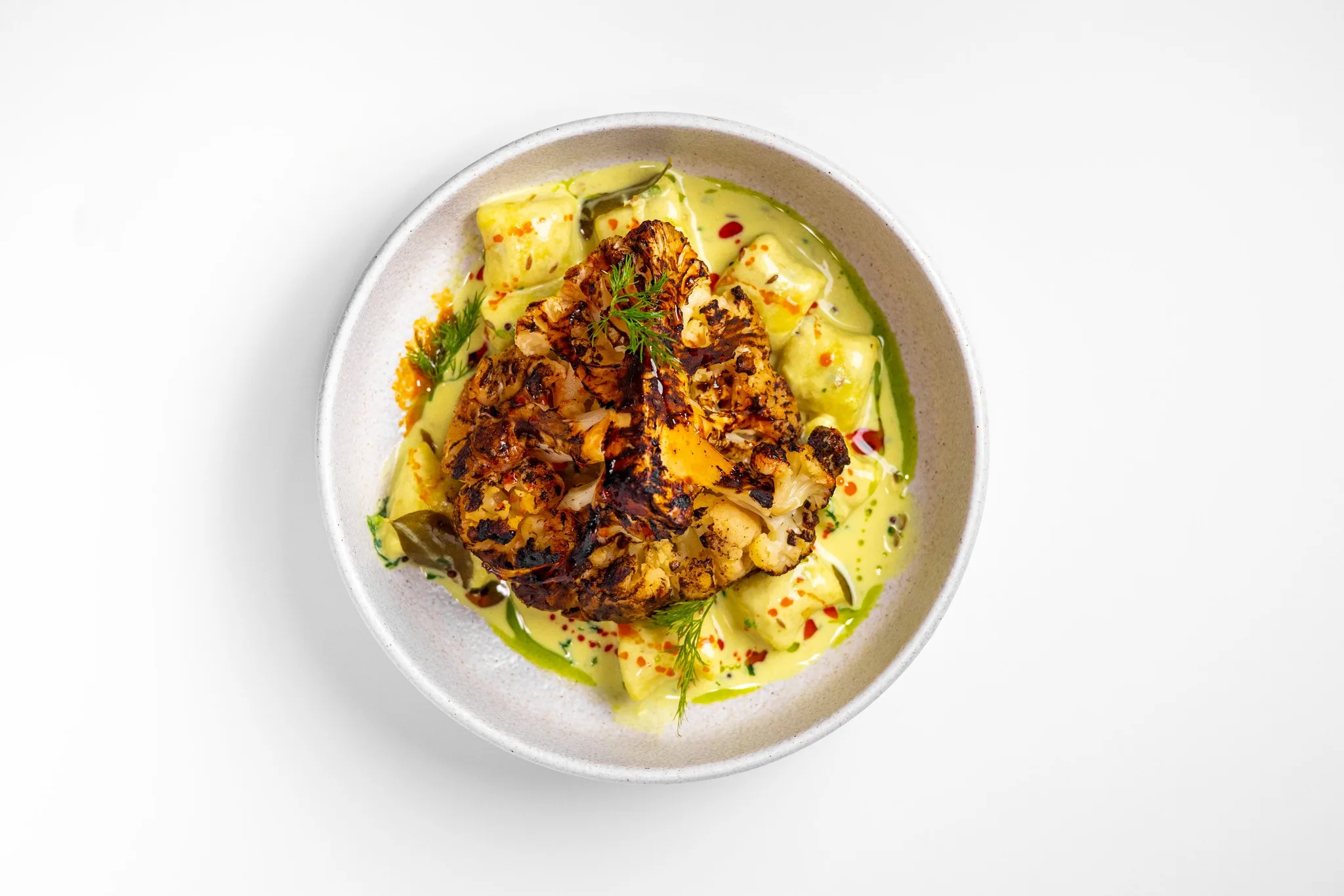 Roasted cauliflower on green sauce with herbs and spices.