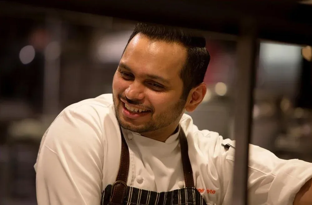A smiling chef in a kitchen setting.