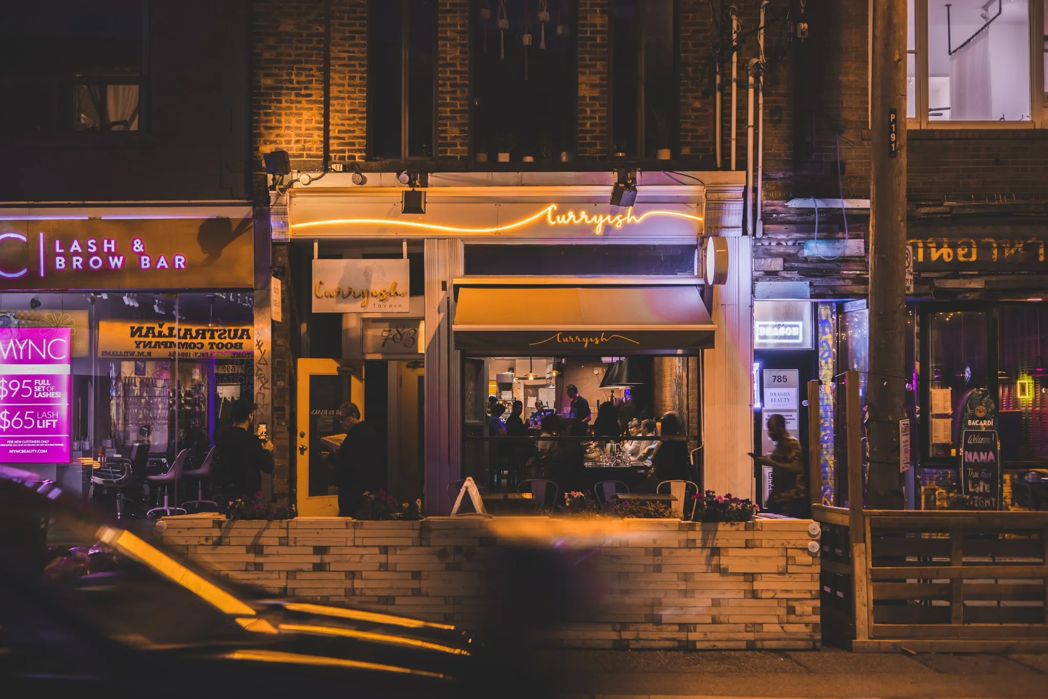 Exterior view of Curryish Tavern with neon signage at night.
