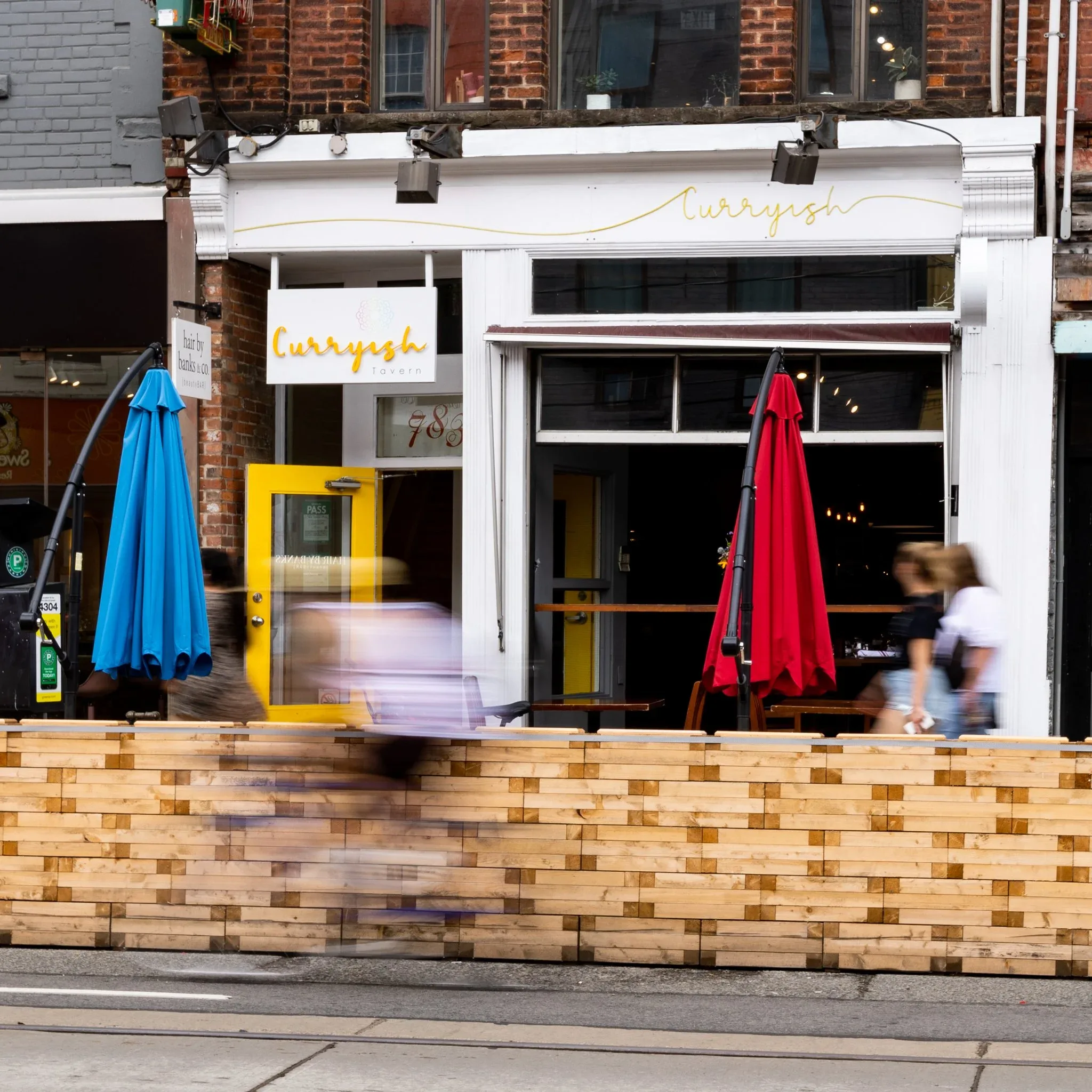 Outdoor seating at Curryish Tavern with colorful umbrellas.