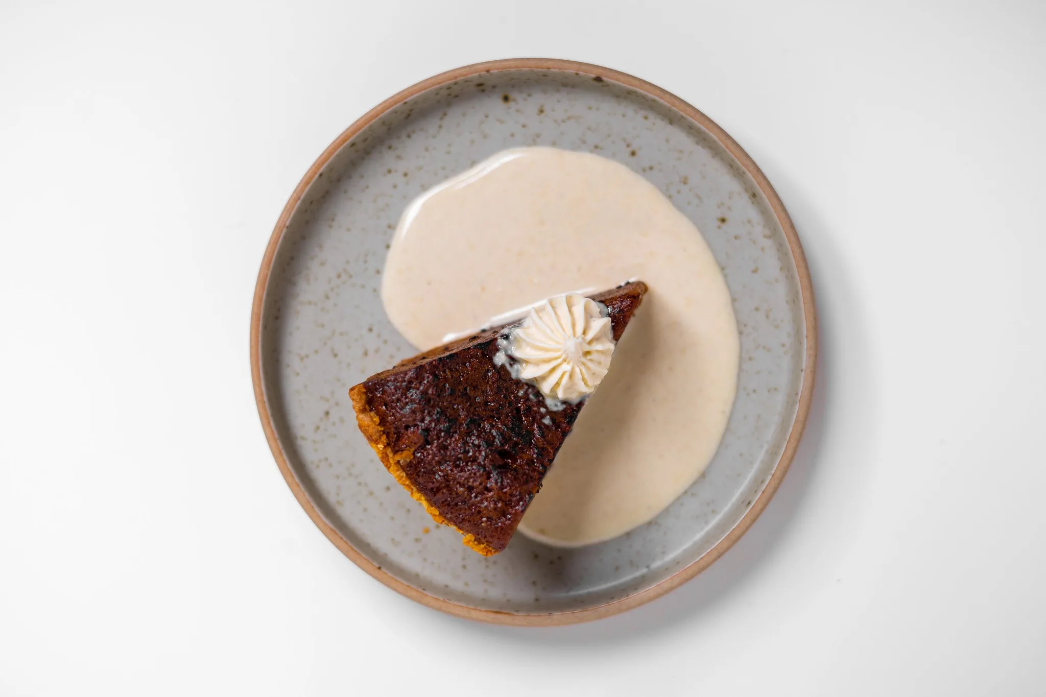 Slice of cake on a plate with whipped cream and sauce.