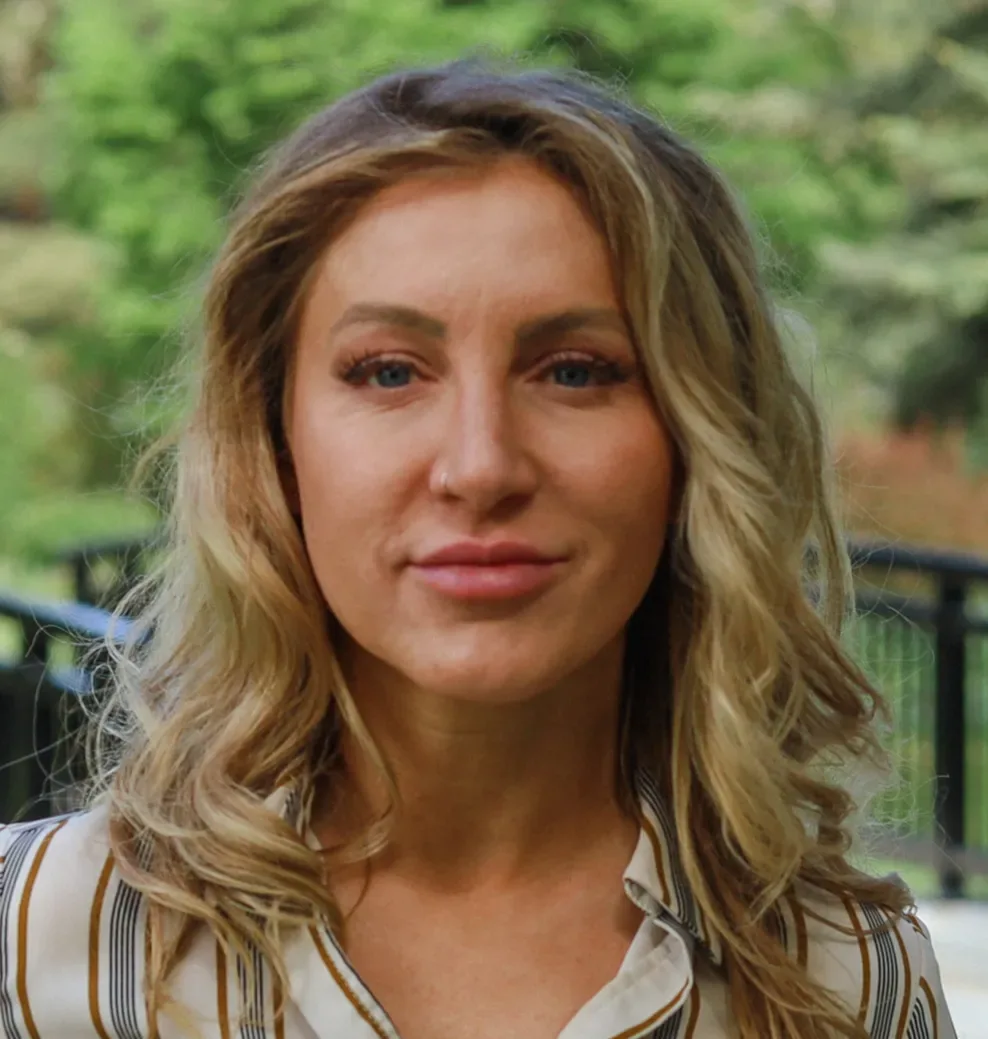 A woman with blonde hair in a striped shirt outdoors.