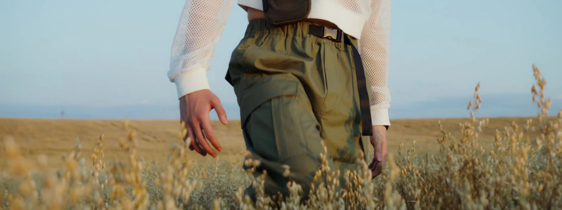 A person walking through a field in casual attire.