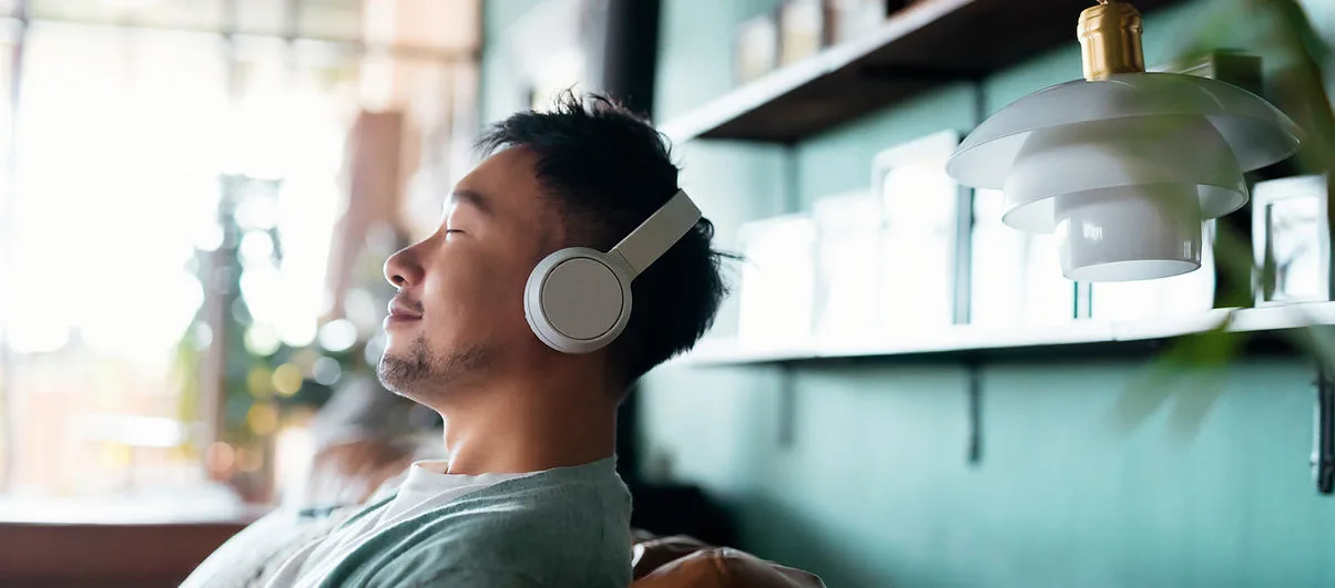 A man relaxing with headphones in a cozy room.