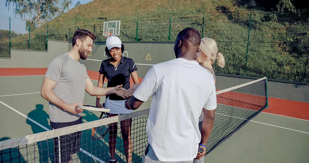 Four people interacting on a tennis court.